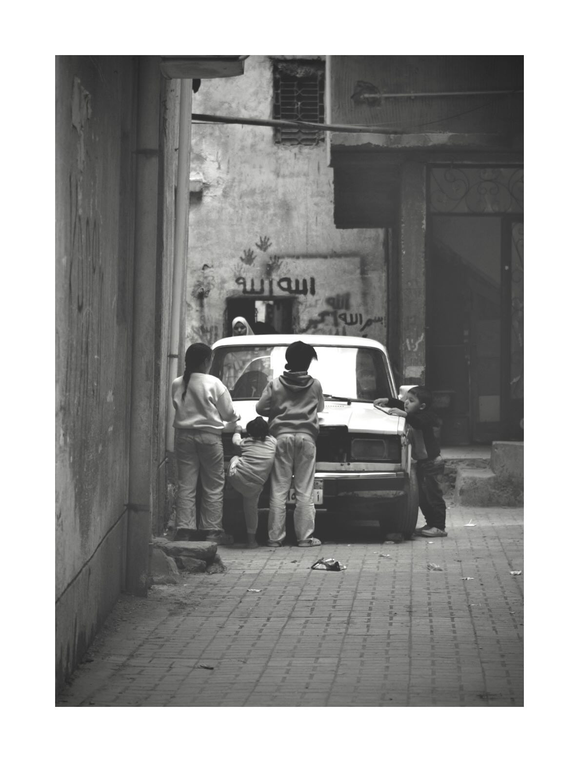 People beside a vehicle in a narrow street
