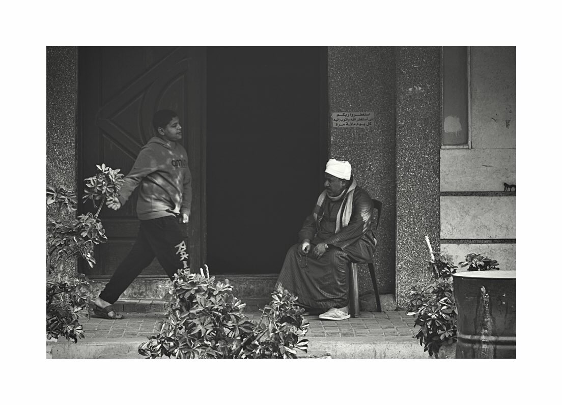 Seated man and passerby at a doorway