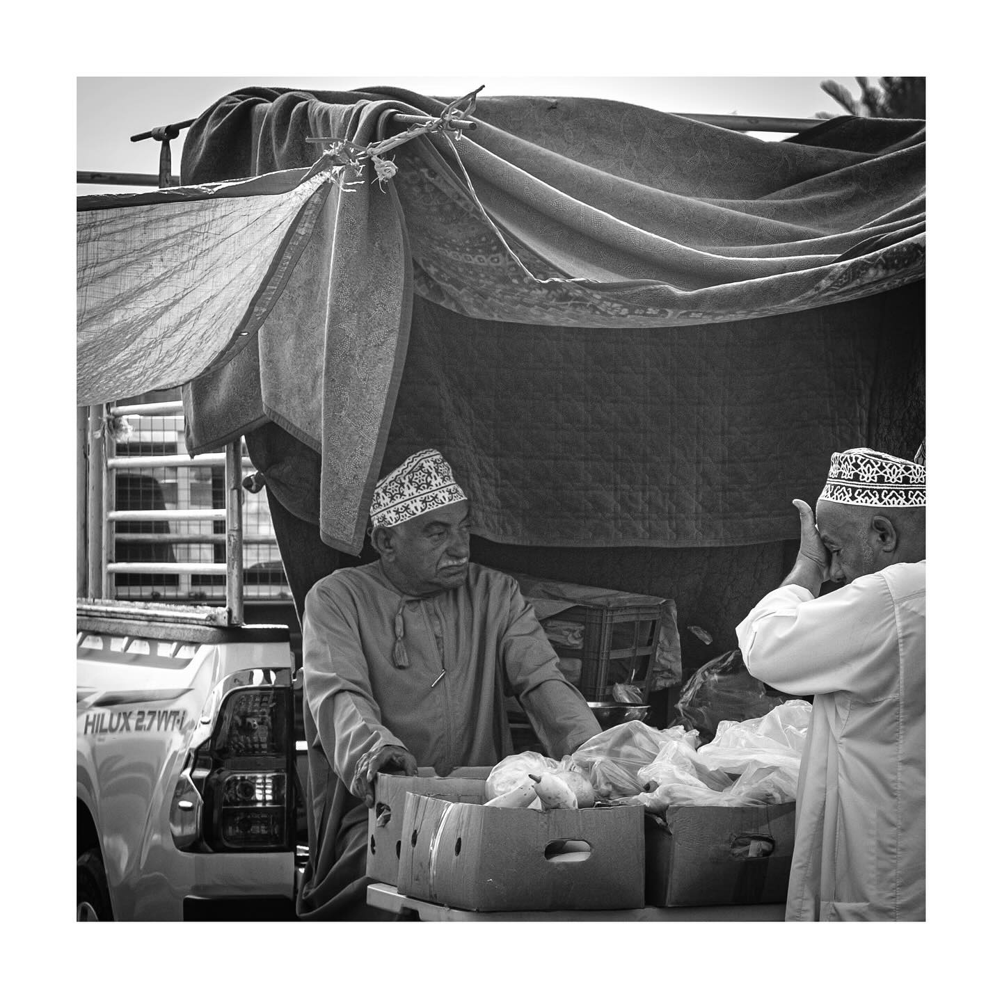 Two men talking across a market stall