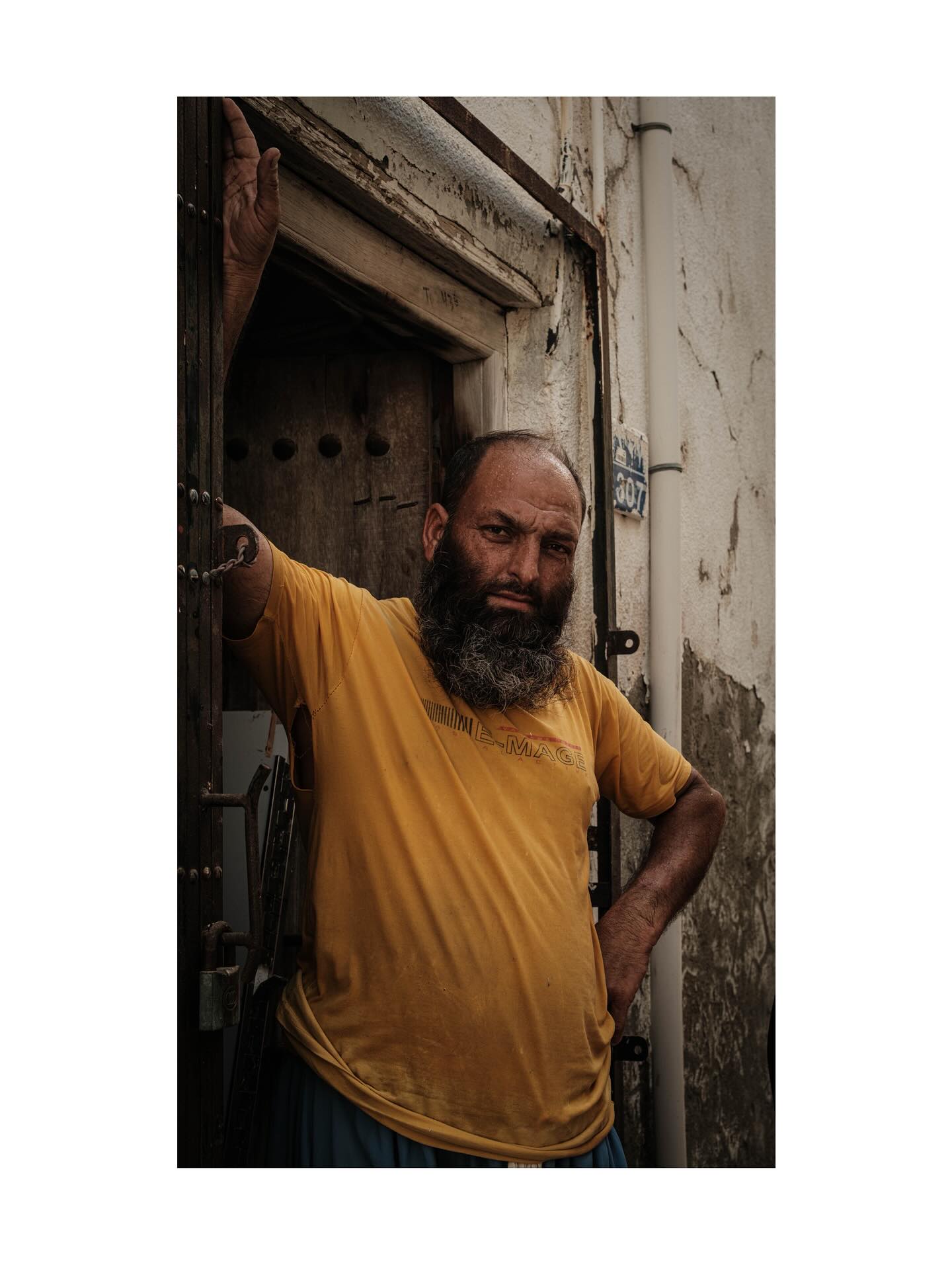 Man in a yellow shirt leaning in a doorway