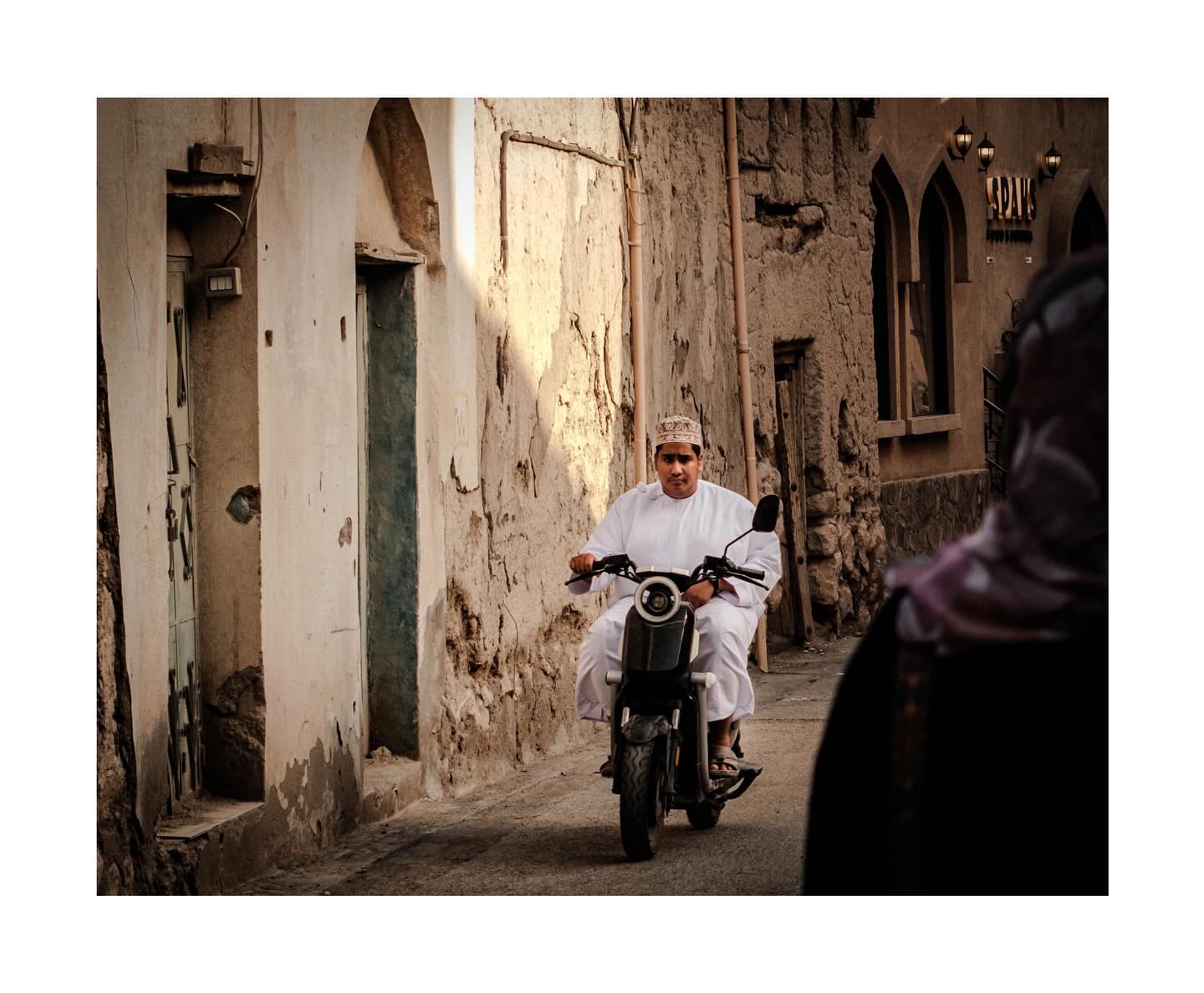 Man riding a motorcycle through an old street