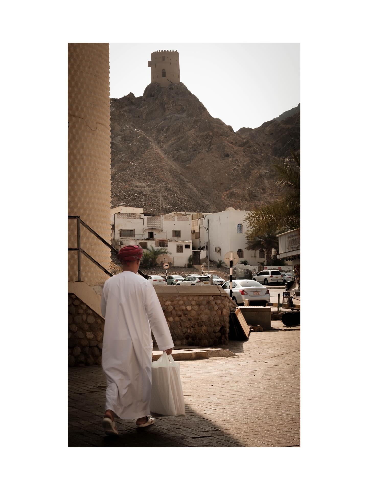 Man walking below a mountain watchtower