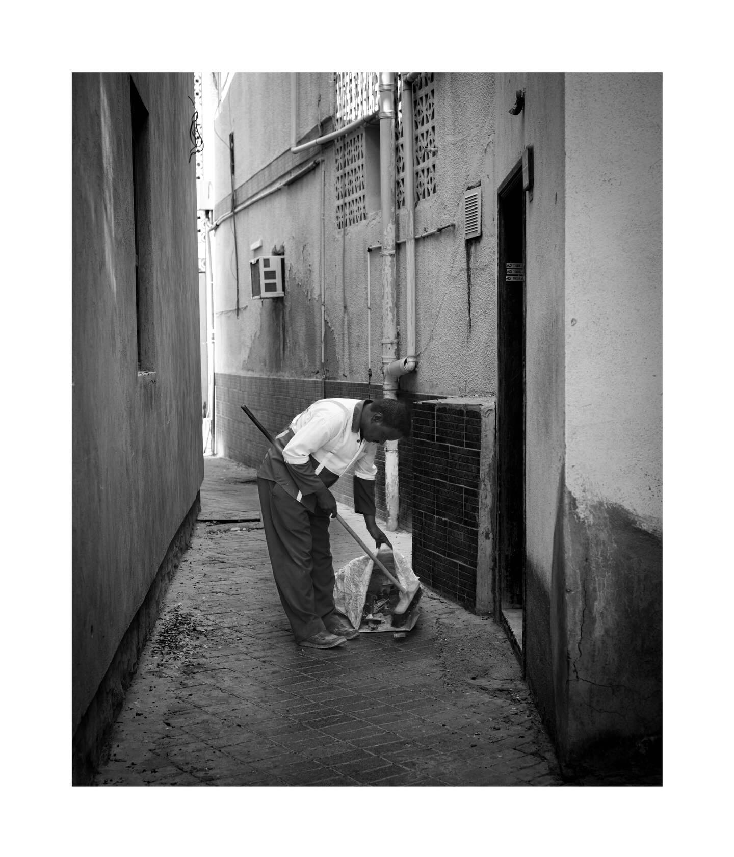 Man sweeping a narrow street