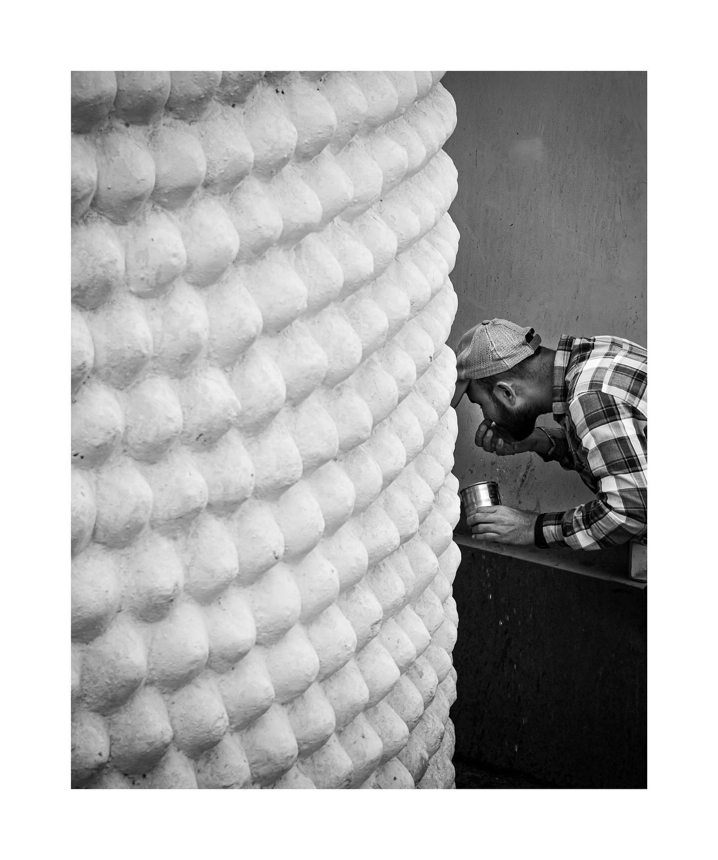 Man leaning beside a textured column