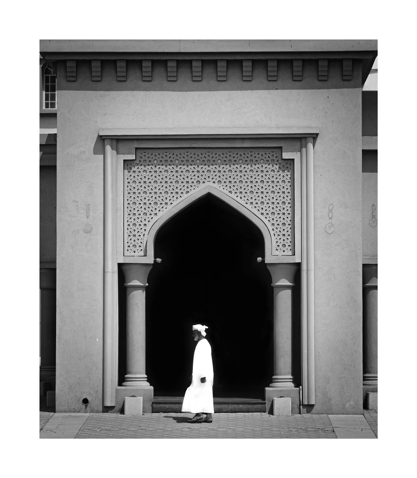 Man walking past an arched entrance