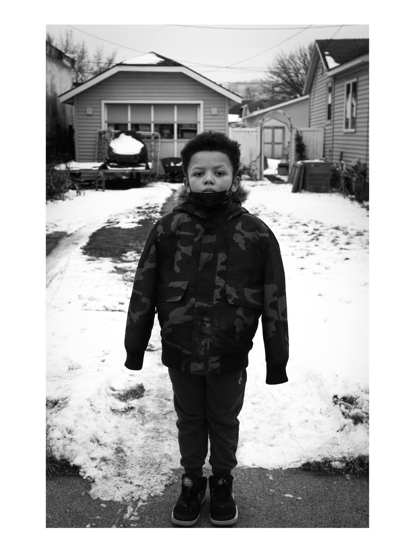 Child standing on a snowy sidewalk