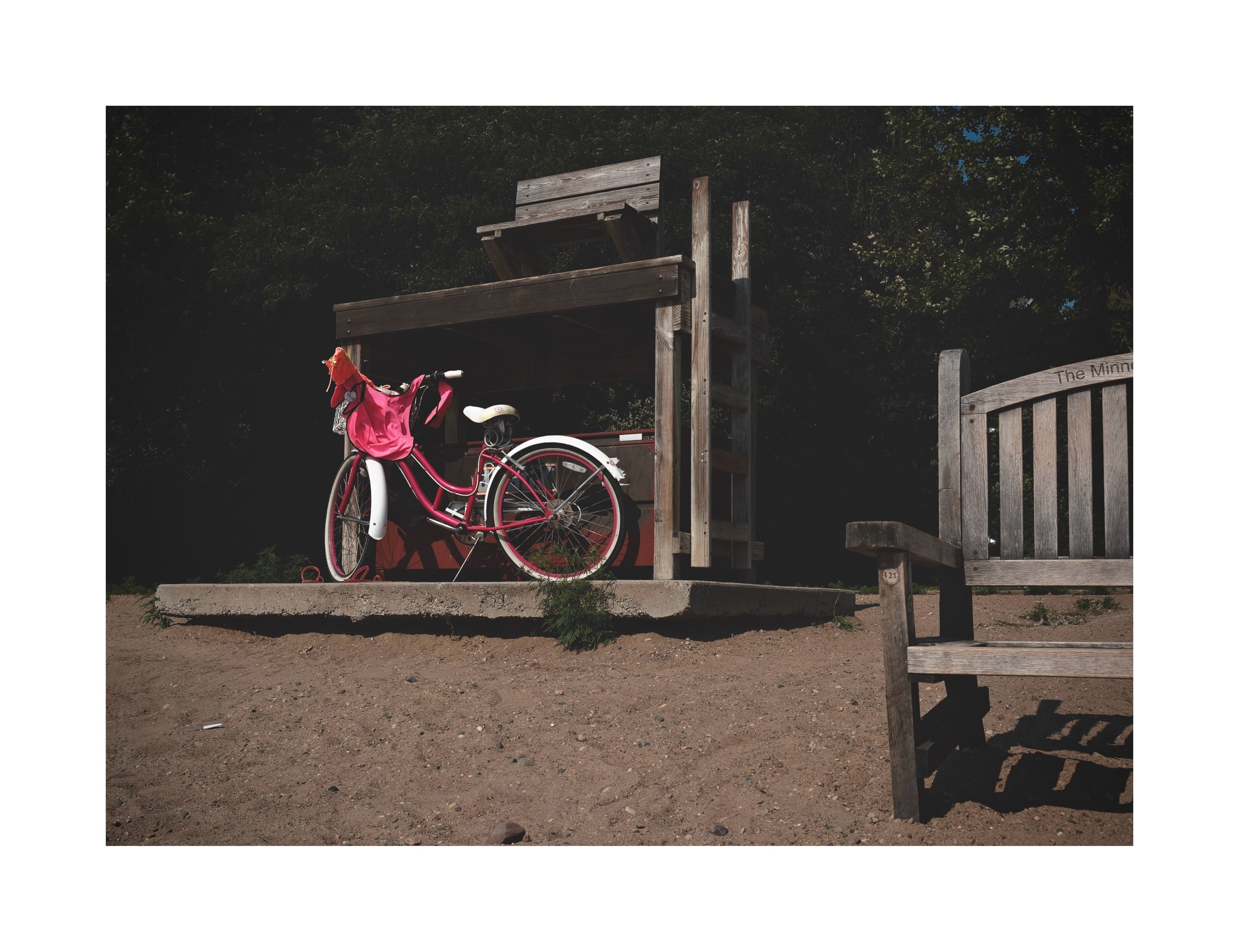 Red bicycle beside a wooden bench